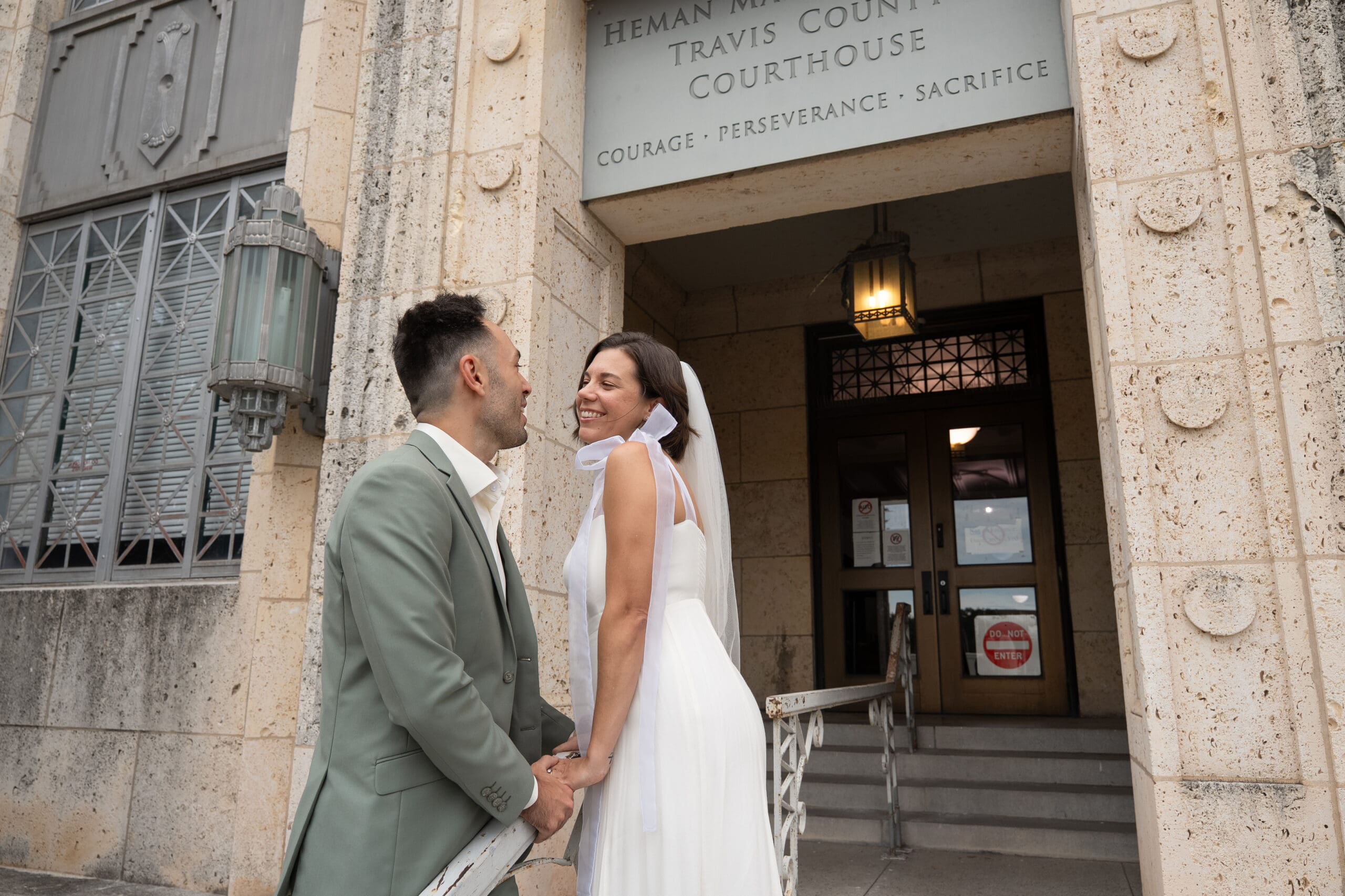 bride and groom looking at each other across from the railing outside Travis County Courthouse in Austin