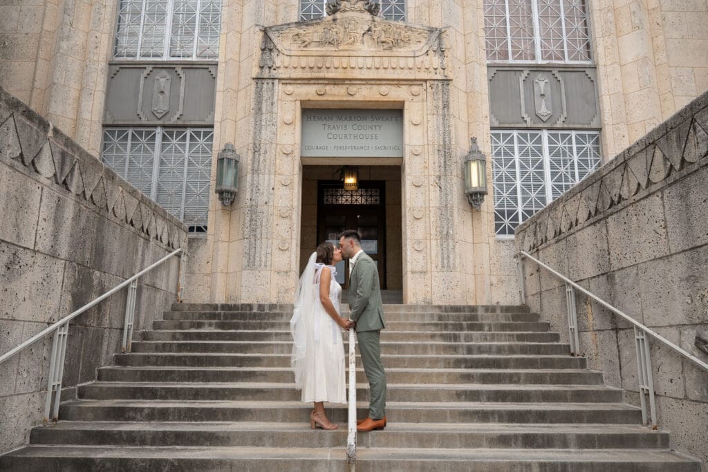 Bride and Groom kiss on the steps of Travis County Courthouse | Where to Elope in Austin