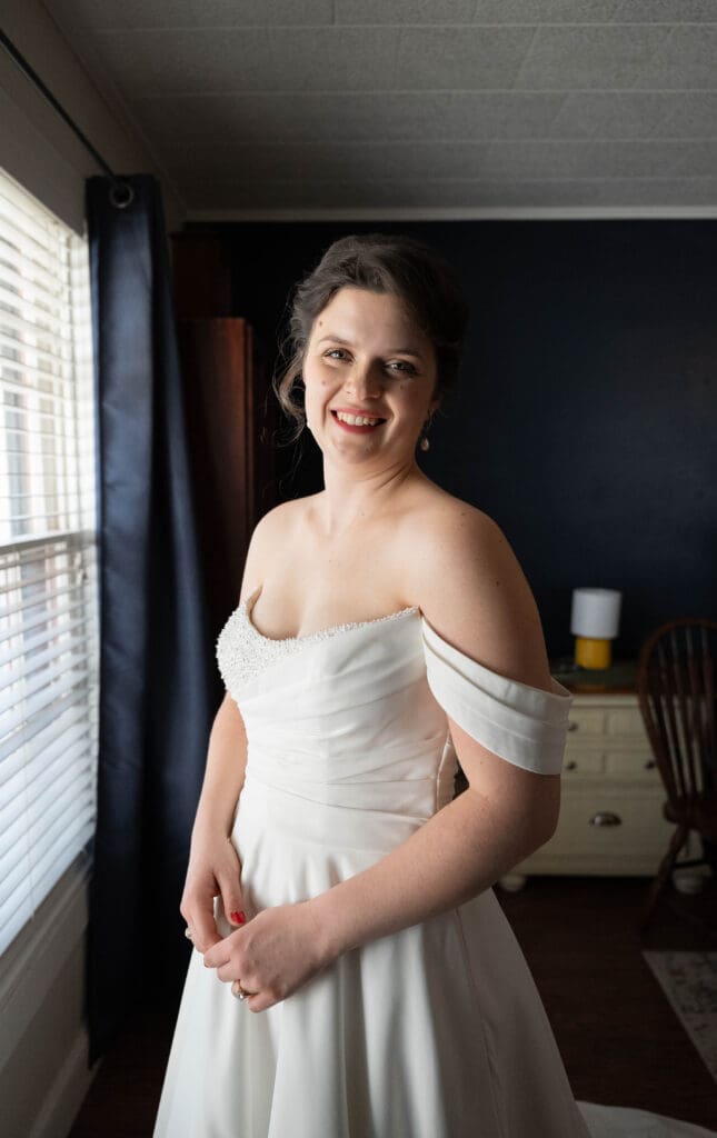 bride smiles at camera in dress in childhood home