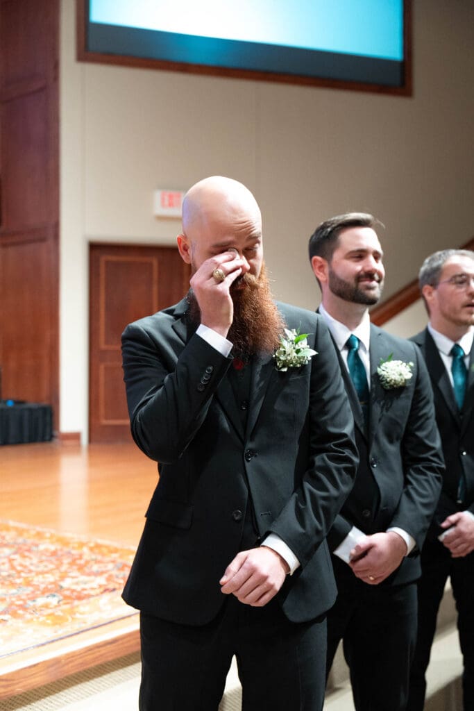 groom wipes tears as he sees his bride down the aisle
