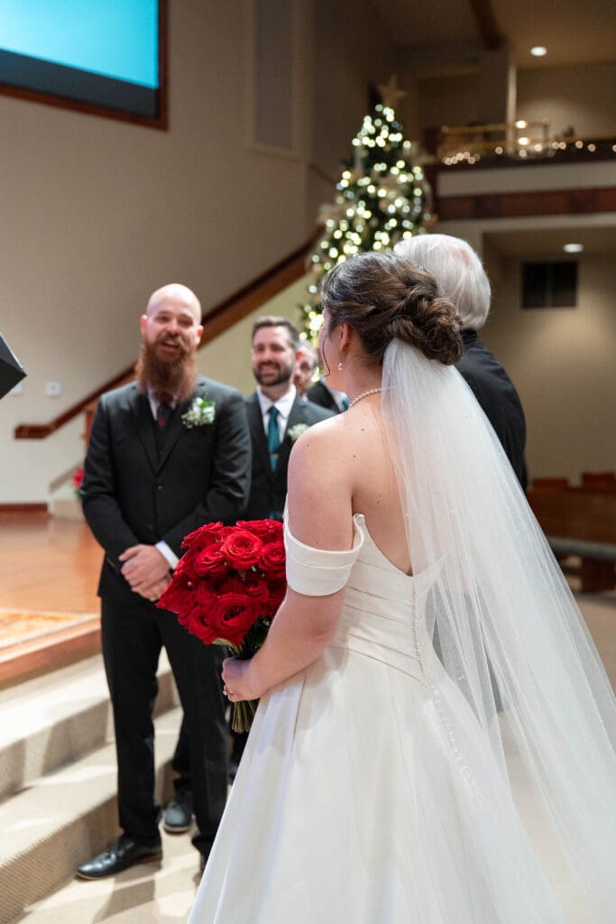 groom smiles at bride as she stops at top of the alter